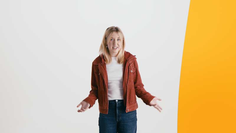 Eine Frau vor einer grauen Wand, die etwas erklären möchte